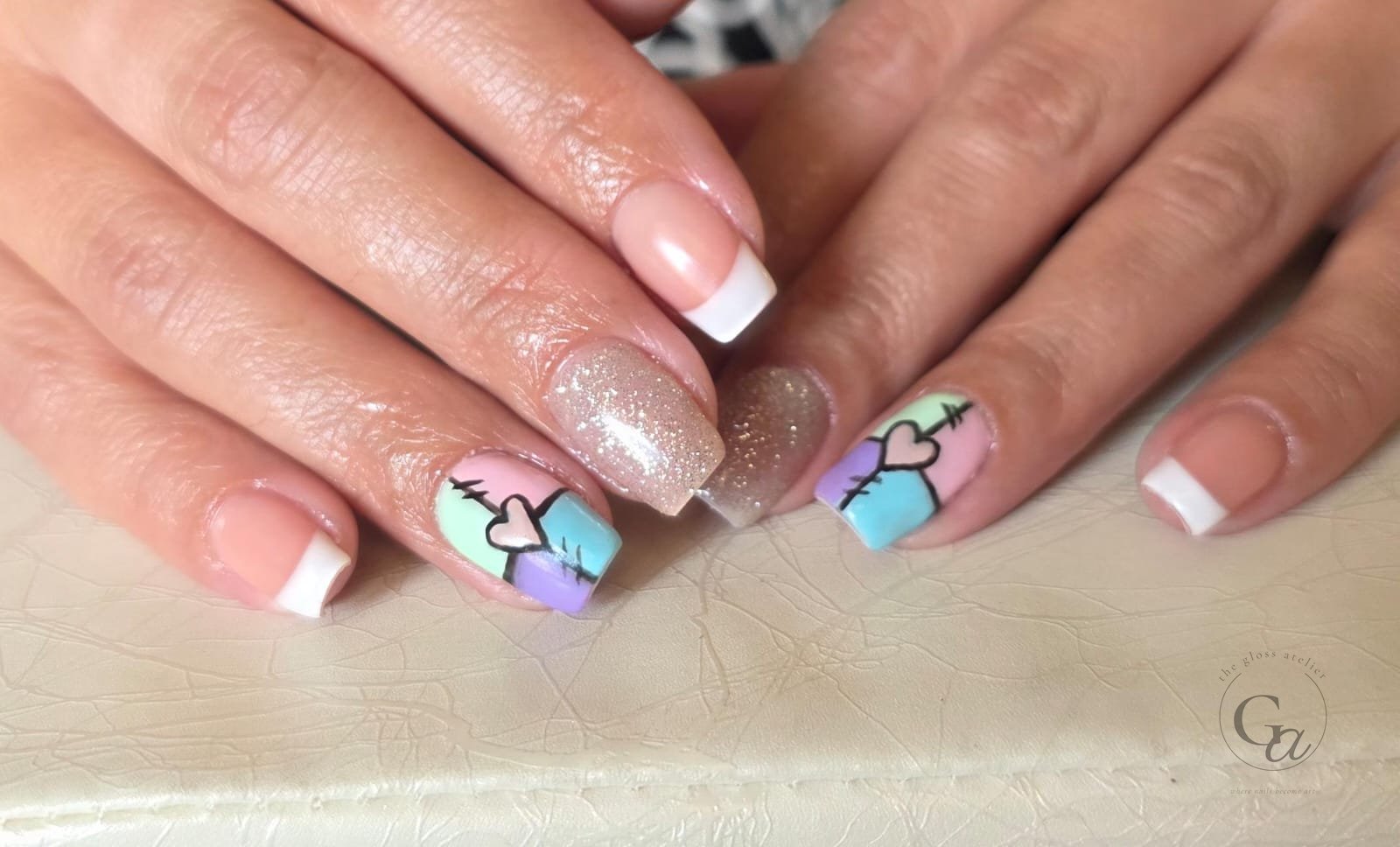 Pastel patchwork hearts with white French tips and a gold glitter accent nail.