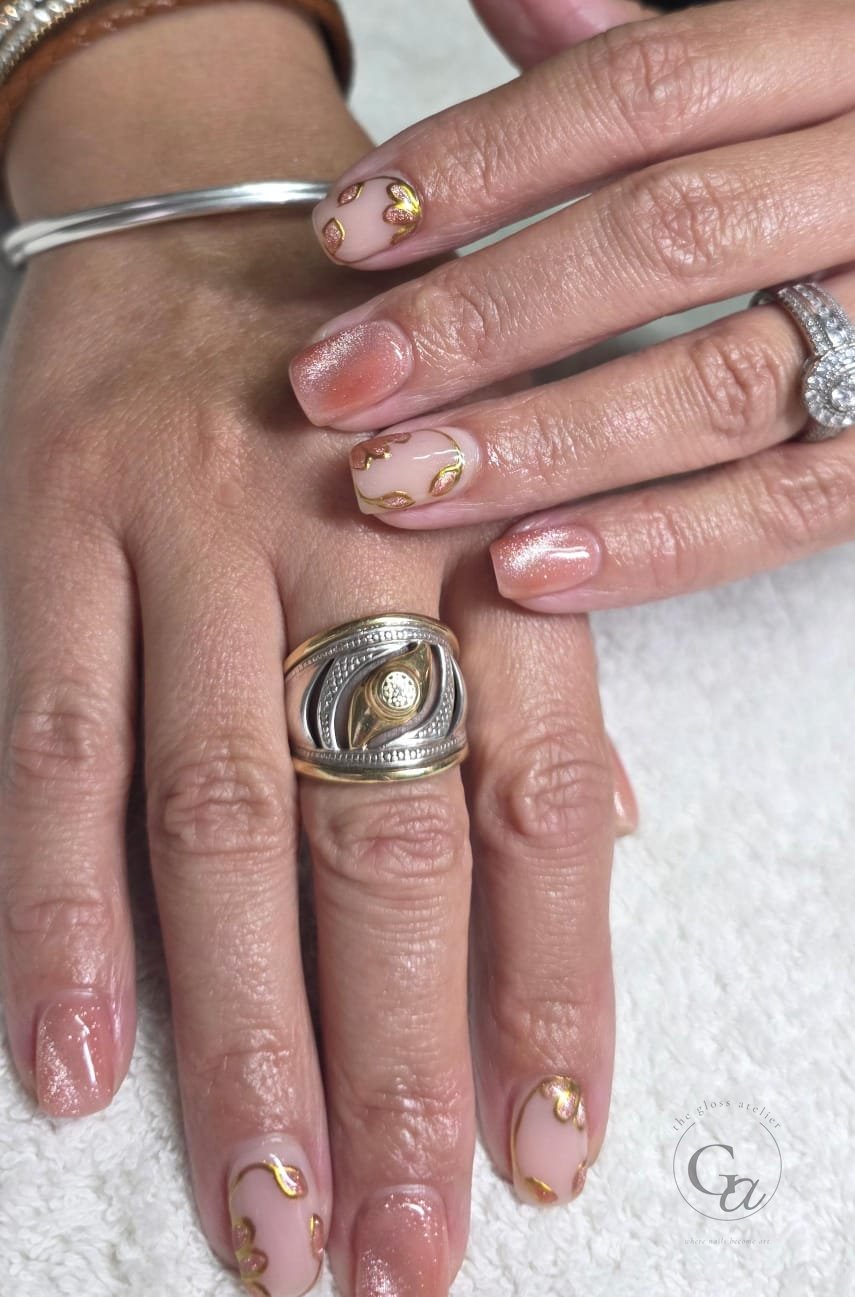 Rose-gold shimmer nails with gold-outlined petals.