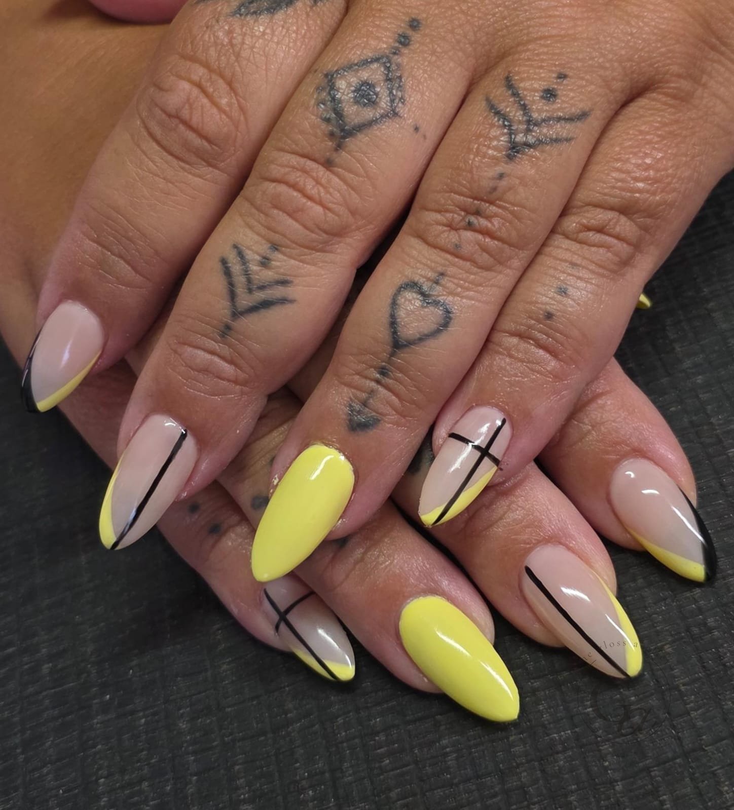 Butter-yellow French tips on almond nails with fine black line work.