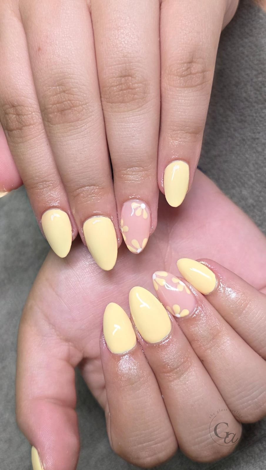 Butter-yellow almond nails with hand-painted daisy accent nails.